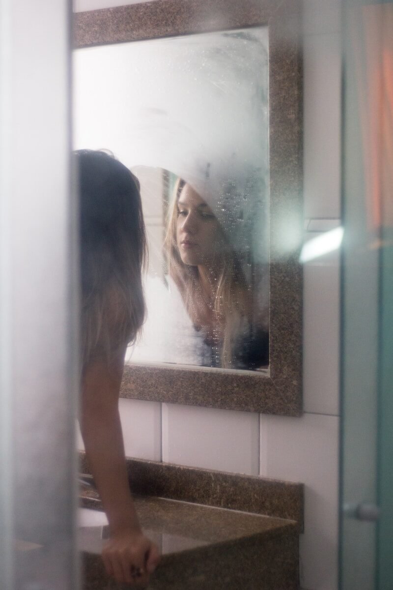 woman looking on wall mirror